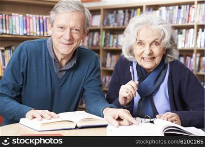 Mature Student Working With Teacher In Library