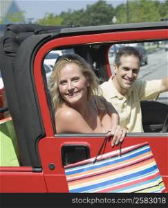 Mature woman and a mid adult man sitting in a car and smiling