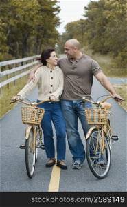 Mature woman and a mid adult man standing with their bicycles and smiling