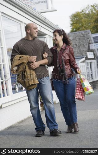 Mature woman and a mid adult man walking with their arm in arm and smiling