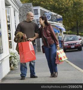 Mature woman and a mid adult woman carrying their shopping bags and smiling
