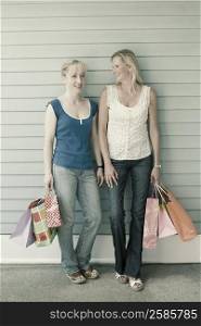 Mature woman and a mid adult woman holding shopping bags and smiling