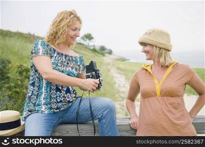 Mature woman and a mid adult woman looking at an instant camera in a park