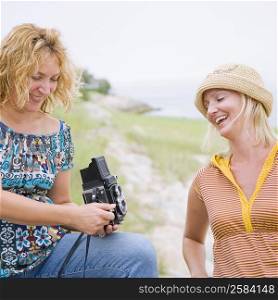 Mature woman and a mid adult woman looking at an instant camera in a park