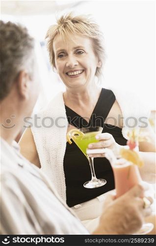 Mature woman and a senior man holding glasses of cocktail and smiling