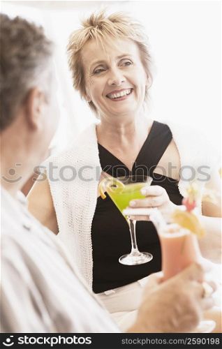 Mature woman and a senior man holding glasses of cocktail and smiling