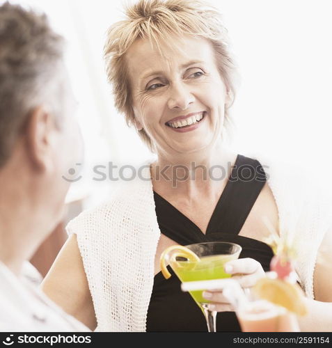 Mature woman and a senior man holding glasses of cocktail and smiling