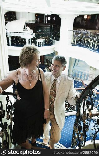 Mature woman and a senior man moving up on a staircase of a ship