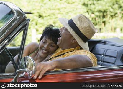Mature woman and a senior man sitting in a convertible car