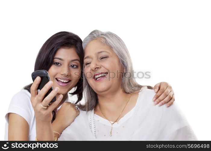 Mature woman and her granddaughter looking at a mobile phone
