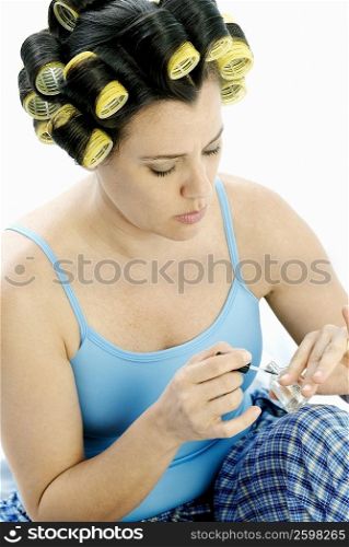 Mature woman applying nail polish on her fingernails