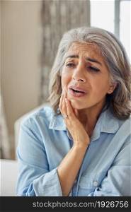 Mature Woman At Home Suffering From Pain With Toothache