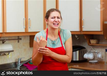 Mature woman checking pulse on wrist. Stressed female in kitchen.. Woman checking pulse on wrist.
