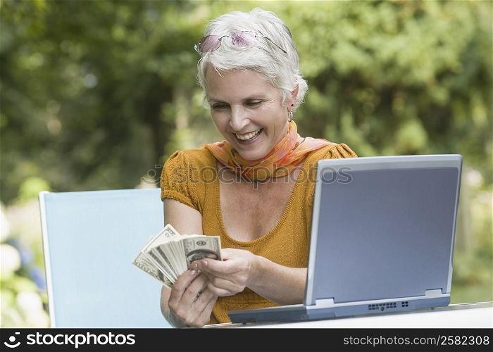 Mature woman counting paper currency and smiling