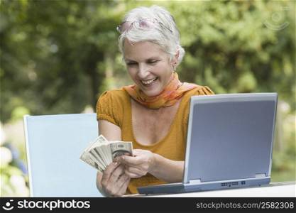 Mature woman counting paper currency and smiling