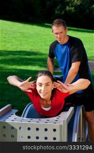 Mature woman does exercises with her personal trainer, having a lot of fun on a sunny day