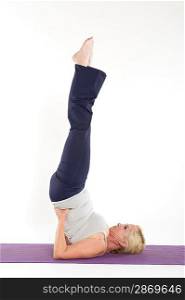 Mature woman doing a yoga pose with feet in the air