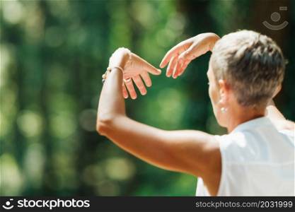 Mature Woman Doing Tai Chi Exercises in the Park. Close Up on Hands Position. Mature Woman Doing Tai Chi Exercises in the Park.