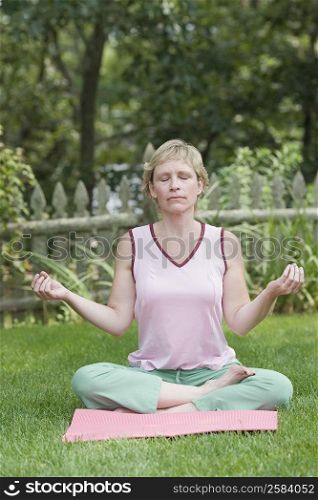 Mature woman doing yoga in a lawn