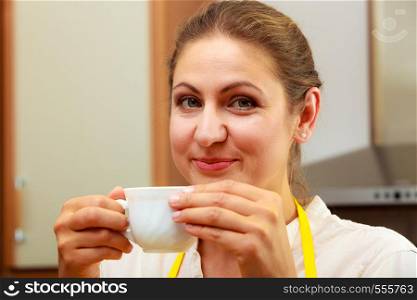 Mature woman drinking cup of coffee in kitchen. Housewife female with hot energizing beverage. Caffeine energy.. Mature woman drinking cup of coffee in kitchen.