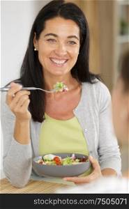 mature woman eating a salad with a friend