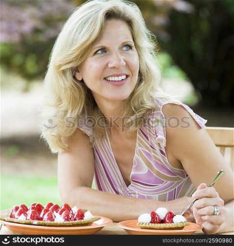 Mature woman eating a strawberry tart and smiling