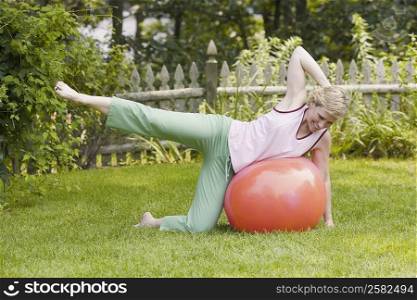 Mature woman exercising with a fitness ball in a lawn