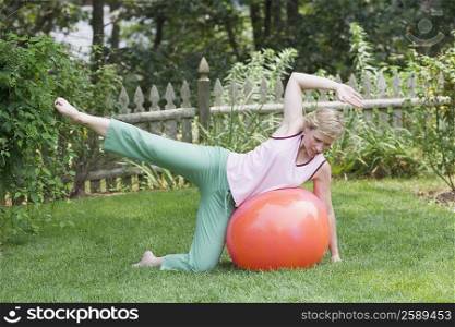 Mature woman exercising with a fitness ball in a lawn