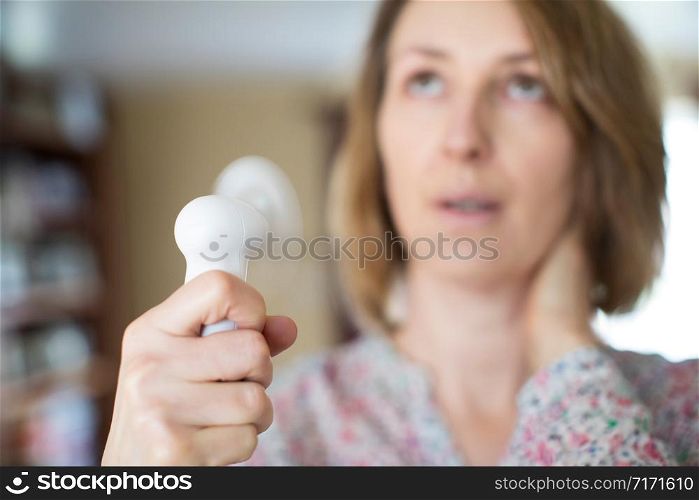 Mature Woman Experiencing Hot Flush From Menopause Using Electric Fan