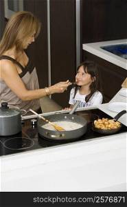 Mature woman feeding her daughter in a kitchen