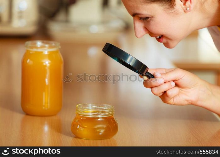Mature woman female inspecting testing honey food with magnifying glass.. Woman inspecting honey with magnifying glass.