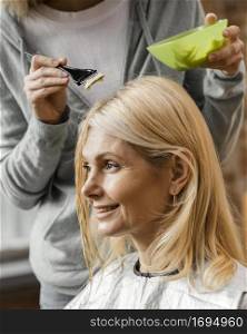 mature woman getting her hair dyed by hairdresser home
