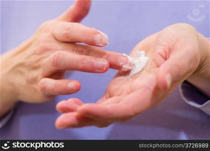 Mature woman has skincare cream on her palm