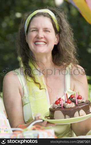 Mature woman holding a birthday cake and smiling