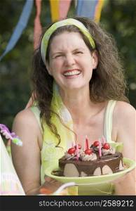 Mature woman holding a birthday cake and smiling
