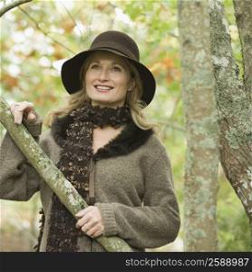 Mature woman holding a branch of tree and smiling