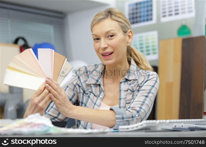 mature woman holding a color swatch in office