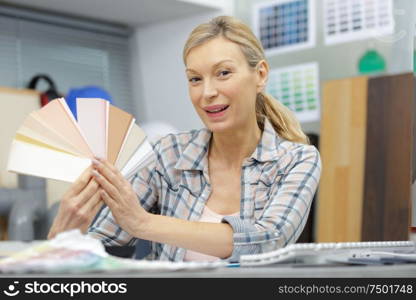 mature woman holding a color swatch in office