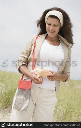Mature woman holding a conch shell and smiling