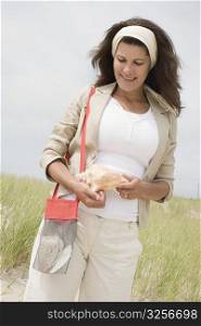 Mature woman holding a conch shell and smiling