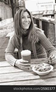 Mature woman holding a glass of chocolate milkshake and smiling