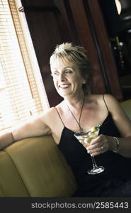 Mature woman holding a glass of cocktail and smiling