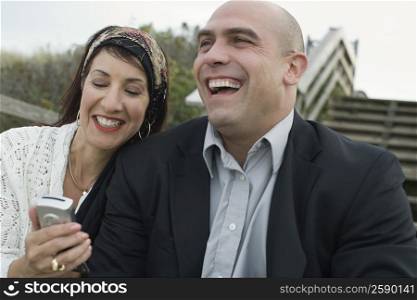 Mature woman holding a mobile phone and smiling with a mid adult man