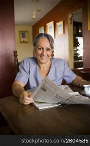 Mature woman holding a newspaper and smiling