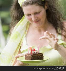 Mature woman holding a plate of a birthday cake slice