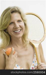 Mature woman holding a tennis racket and a tennis ball