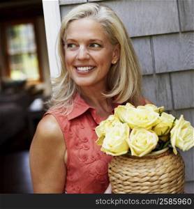 Mature woman holding flowers in a vase and smiling