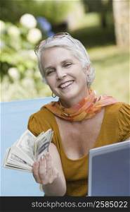 Mature woman holding paper currency and smiling