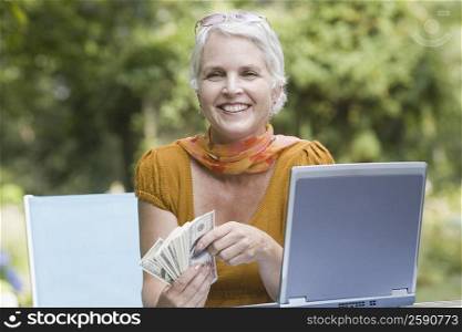 Mature woman holding paper currency and smiling