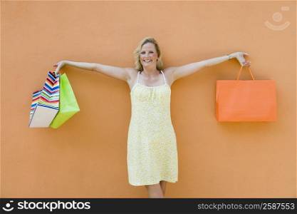 Mature woman holding shopping bags with her arm outstretched and smiling